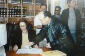 Η Γ.Γ. του ΚΚΕ Αλέκα Παπαρήγα γράφει στο βιβλίο επισκεπτών του Αναγνωστηρίου κατά την εκεί επίσκεψή της (16-5-2004). 