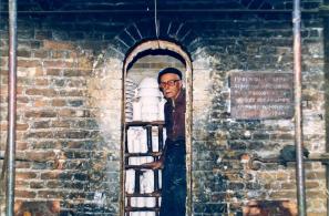 Ο Νίκος Κουρτζής στο φούρνο του. Δεξιά φαίνεται πινακίδα που αναγράφει: ΠΡΟΤΥΠΟΣ ΚΛΙΒΑΝΟΣ ΚΕΡΑΜΙΚΗΣ ΑΝΕΓΕΡΘΕΙΣ ΜΕ ΤΗΝ ΒΟΗΘΕΙΑΝ ΤΟΥ ΕΘΝΙΚΟΥ ΟΡΓΑΝΙΣΜΟΥ ΕΛΛΗΝΙΚΗΣ ΧΕΙΡΟΤΕΧΝΙΑΣ. 1964» 