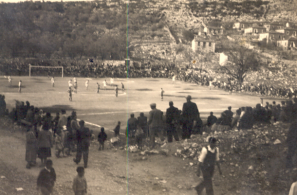 Φάση ποδοσφαιρικού αγώνα στο παλιό γήπεδο. Κερκίδες δεν υπήρχαν. Δεξιά μερική άποψη της συνοικίας του Μαυριώτη (Συνοικισμός ή Προσφυγικά).